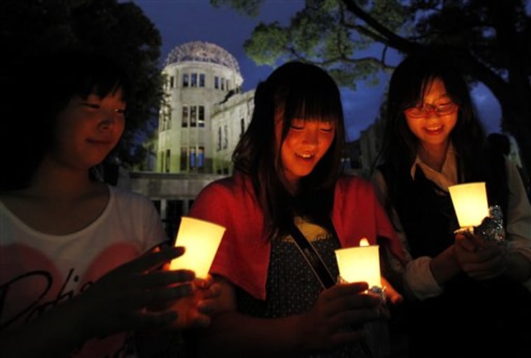 Women join a candle vigil in front of the illuminatd Atomic Bomb Dome  in Hiroshima, western Japan, Thursday, Aug. 5, 2010, on the eve of the 65th anniversary of the world's first atomic bomb attack. (AP Photo/Shuji Kajiyama)
